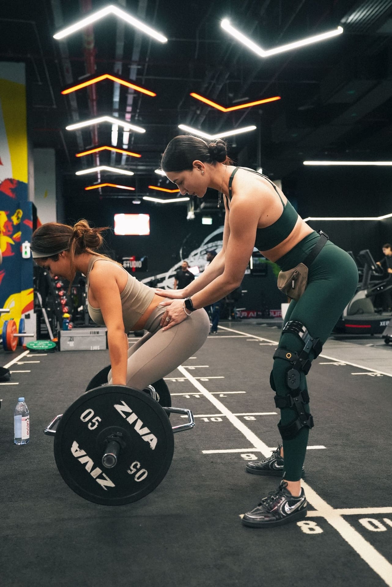 Female Project Reshape coach cueing a client through a deadlift hinge