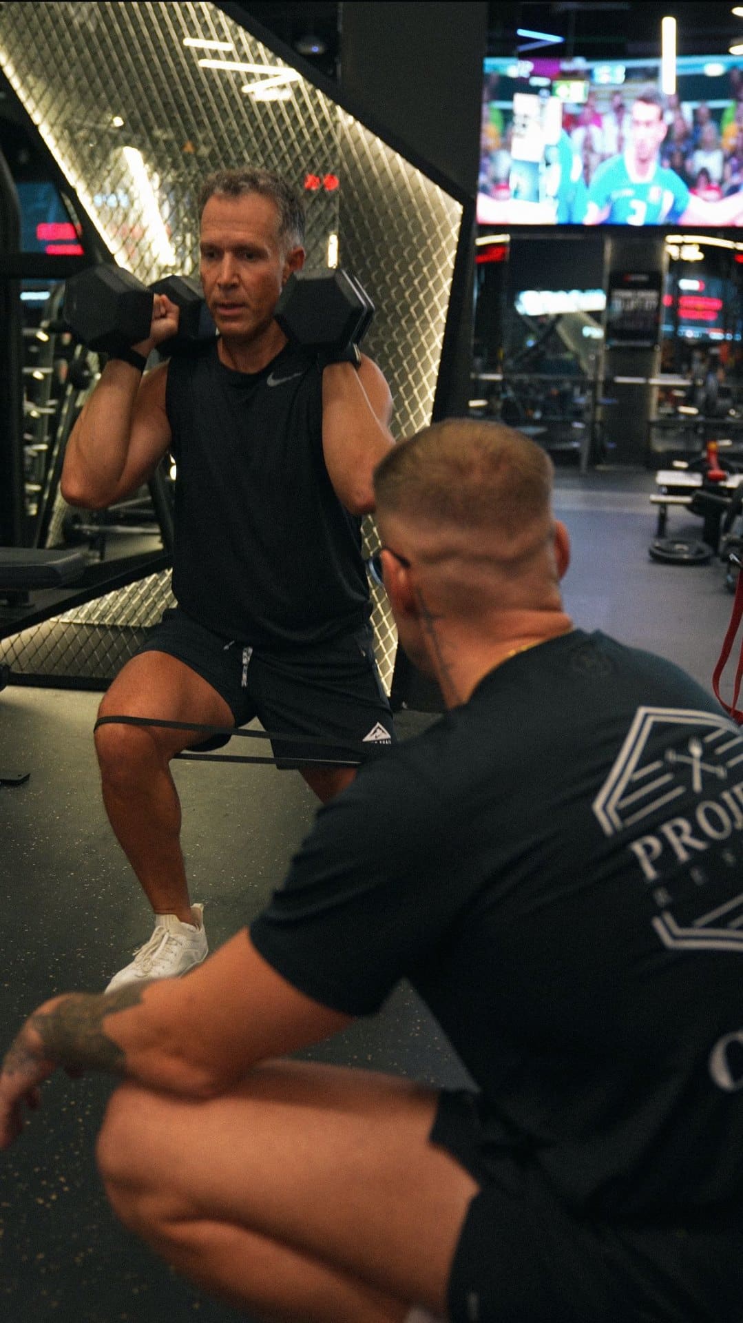 Project Reshape coach demonstrating front-rack squat form to a client